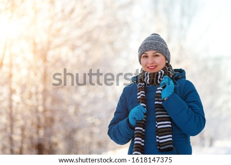 portrait of a young happy girl woman in winter clothes. in the winter snow forest Park