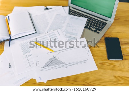 Business graph papers on a table and laptop with green screen.
