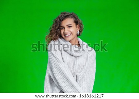 Beautiful natural young smiling girl wearing knitted sweater and posing on green background.