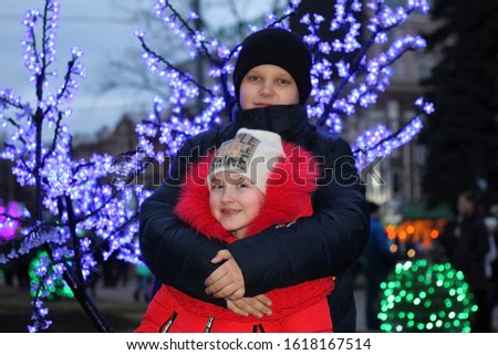 A boy hugs a girl on the background of new year's decor