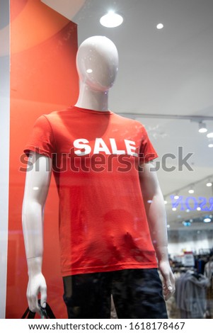 some mannequins wear a red shirt with the word "sale" in the window of an Italian clothing and fashion store. During the winter sales in January.