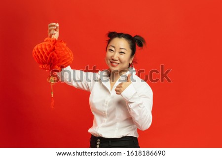 Decorations for mood. Happy Chinese New Year 2020. Asian young woman holding lantern on red background in traditional clothing. Smiling, thumb up. Celebration, human emotions, holidays. Copyspace.