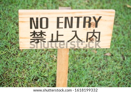 The sign on the label with words"No ENTRY" on a green lawn.