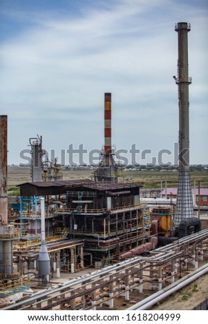 Oil refinery plant in desert. Distillation column, equipment, and factory chimney. Blue sky with clouds.