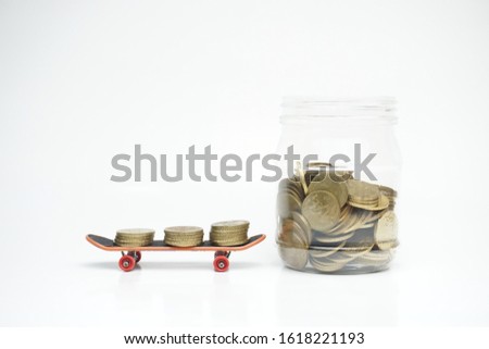 Financial and savings concept: Toy skateboard with coins and bottle glass isolated on white background 