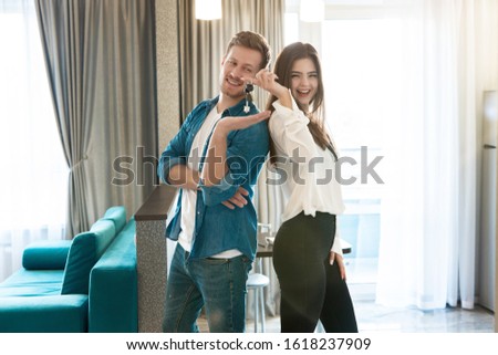 young happy couple man and woman standing in their new cosy appartments after successful real estate deal both smiling wife holding keys
