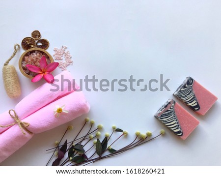 Pink towel and natural oil soap,  plumeria flower, luffa and Himalayan pink salt on white background.