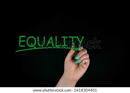 Equality Handwritten by a woman With Green Marker on black background, concept of equality between women and men