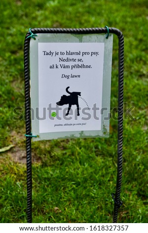An information sign in the park in Prague in Czech republic saying, "Here it is mainly for dogs. Don't be surprised when he runs up to you." A "Please clean up after your dog!"