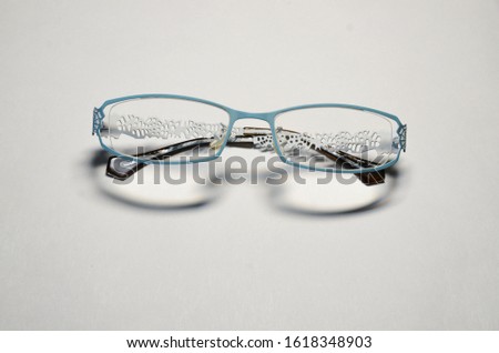 Optics. The medicine. On a white background, women's glasses with transparent lenses in a blue openwork metal frame.