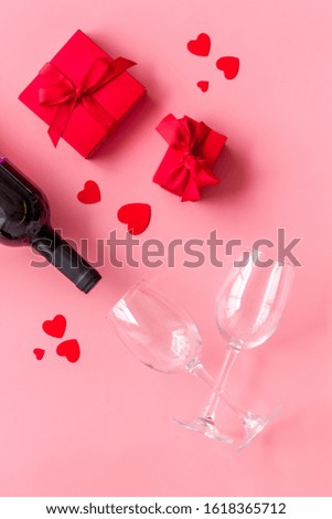 Valentines day table. Wine, present box and glasses on pink background top-down