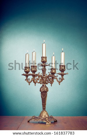 Vintage brass candelabrum with five burning candles in front mint green background