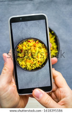 Hands make photo of food with smartphone. Phone photography of Indian basmati rice for blogging in trendy social media style