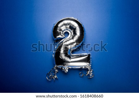 Silver Number Balloon 2 on blue background. Holiday Party Decoration or postcard concept with top view on blue background