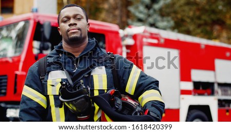 Portrait of african american Firefighter in protective suit with oxygen mask and helmet in hands. Firefighter portrait on duty


