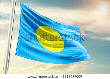 Palau national flag cloth fabric waving on the sky with beautiful sun light