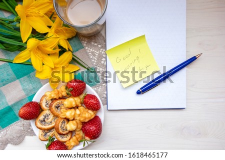 Coffee with sweets - pretzels with poppy seeds, fresh red strawberries and the inscription in the notebook: Good morning, my Love. The view from the top. The concept of Breakfast for Valentine's Day