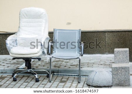 Modern white leather armchair and plastic office chair. New furniture for office left outdoor. Moving to new office