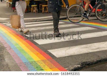 Gay pride flag, Rainbow flag of the LGBT community on crosswalk with people crossing in Paris. LGBT flag as a symbol of love, freedom, equality, rights concepts in daily life.