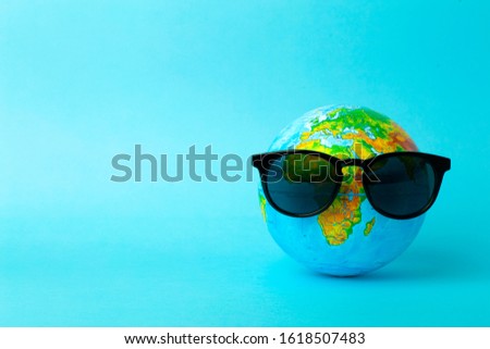Globe in sunglasses on a blue background. Tourism, ecology, vacation and globalism concept. Minimal creative.