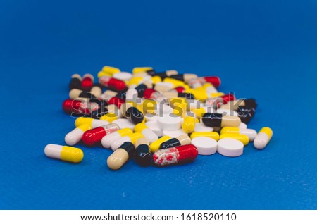 heap of pills of different colors on a blue background