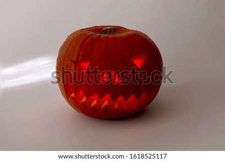 Halloween orange pumpkin with evil smile isolated on a grey background.