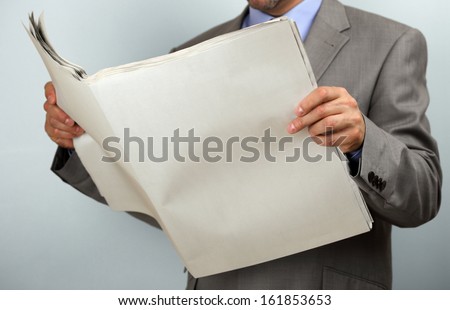 Businessman holding and reading a blank newspaper with copy space