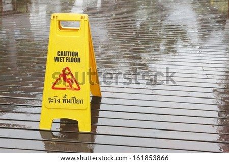 Sign warning of a slipping due to rain on a wooden floor