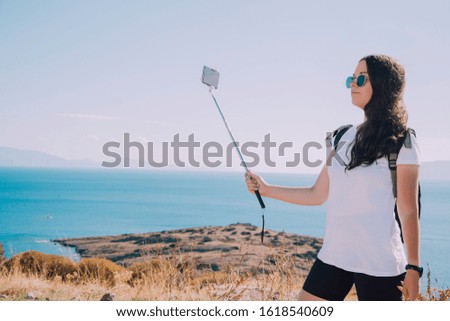 Girl makes selfie on the background of the sea.Traveling in Turkey, Bodrum.Blogger traveler takes photo.Brunette girl of european appearance. Young girl makes photo on the phone.Selfie on smartphone.