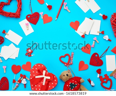 cardboard boxes in the form of a heart, a small teddy bear, white blank business cards with clothespins on a blue background, decor and objects for Valentine's Day, flat lay, copy space