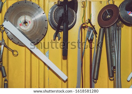 A set of tools on a yellow wall. Concept of work in a home workshop, doing homework. Tools such as the grinding wheel, saw hang on the wall.