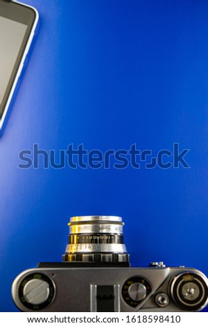 film camera and a fragment of a mobile phone lie on a blue background. Cover. Web banner. Element for design.