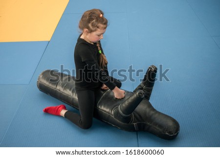 Baby attacks a punching bag in the form of a man. A little girl sits on top on a training mannequin and works off punches. The child beats the training dummy with his hands