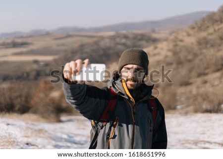 Bearded man making selfie with hills view