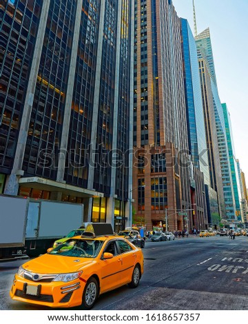 Yellow taxi on road. Street view in Financial District of Lower Manhattan, New York of USA. Cityscape with skyscrapers at United States of America, NYC, US. American architecture. Mixed media.