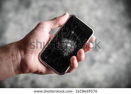 Smart cell phone with a broken screen in hand