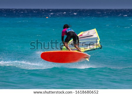 Professional freesyle windsurfer riding waves and jumping at sunny windy day in the Atlantic ocean. Windsurfing, extreme sport. Canary Isalnds, Fuerteventura, Sotavento