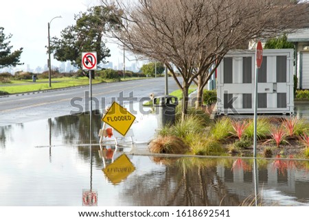 Intersection submerged, flooded after recent rains. Warning signs up to prepare drivers for possibly water damage to vehicle due to flooding, don't drive through flooded roads.