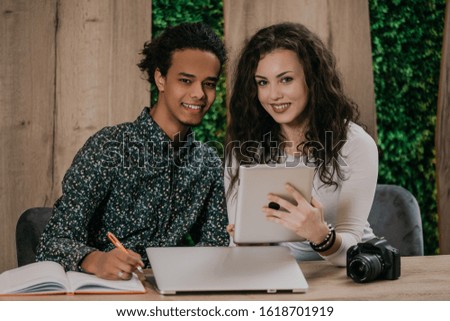Young african man and american woman working in modern coworkong space with laptop and tablet