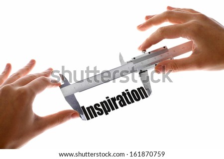 Two hands holding a caliper, measuring the word "Inspiration".