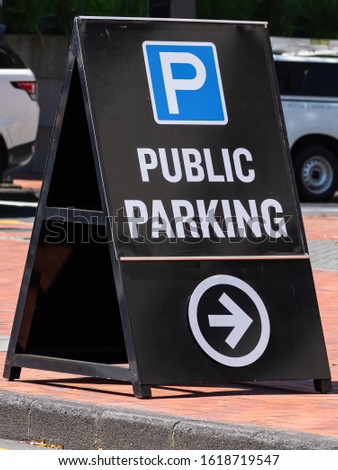 View of public parking sandwich board with white letters on black background