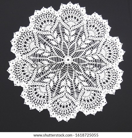 Crocheted openwork white napkin on a black background Royalty-Free Stock Photo #1618725055
