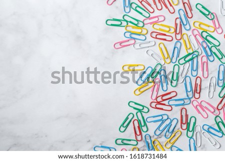Colorful paper clips on white marble texture background.