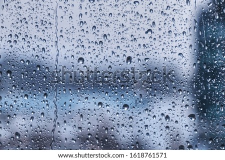 Drops of rain on window during the storm with blur background, water drops background