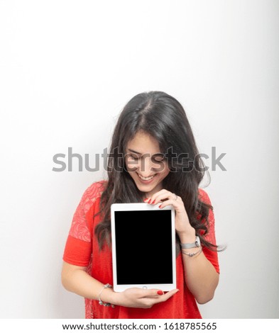 young girl with long black hair dressed in red, holding the tablet with the black screen for text. Copy space, mockup