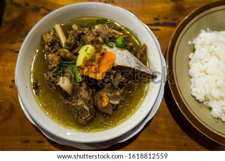 Soft focus images of Beef Spare Ribs soup served with rice put on the wooden table. Photographed from above at close range.