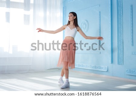 Full-length portrait of young woman dancing in studio near window. Spring concept. March 8. beautiful girl in stylish clothes.