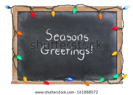 Seasons Greetings written in white chalk on a black chalkboard  surrounded by festive lights isolated on white