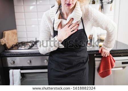 Woman having heart / chest pain and problems during house work in the kitchen.