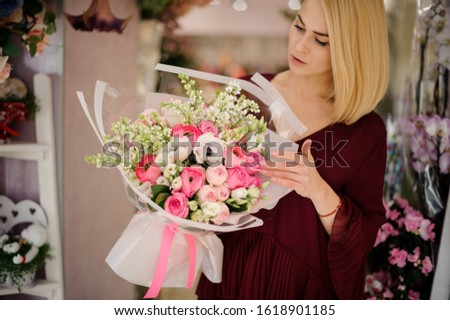 Beautiful woman in dark red dress with bouquet of pink roses and white poppies